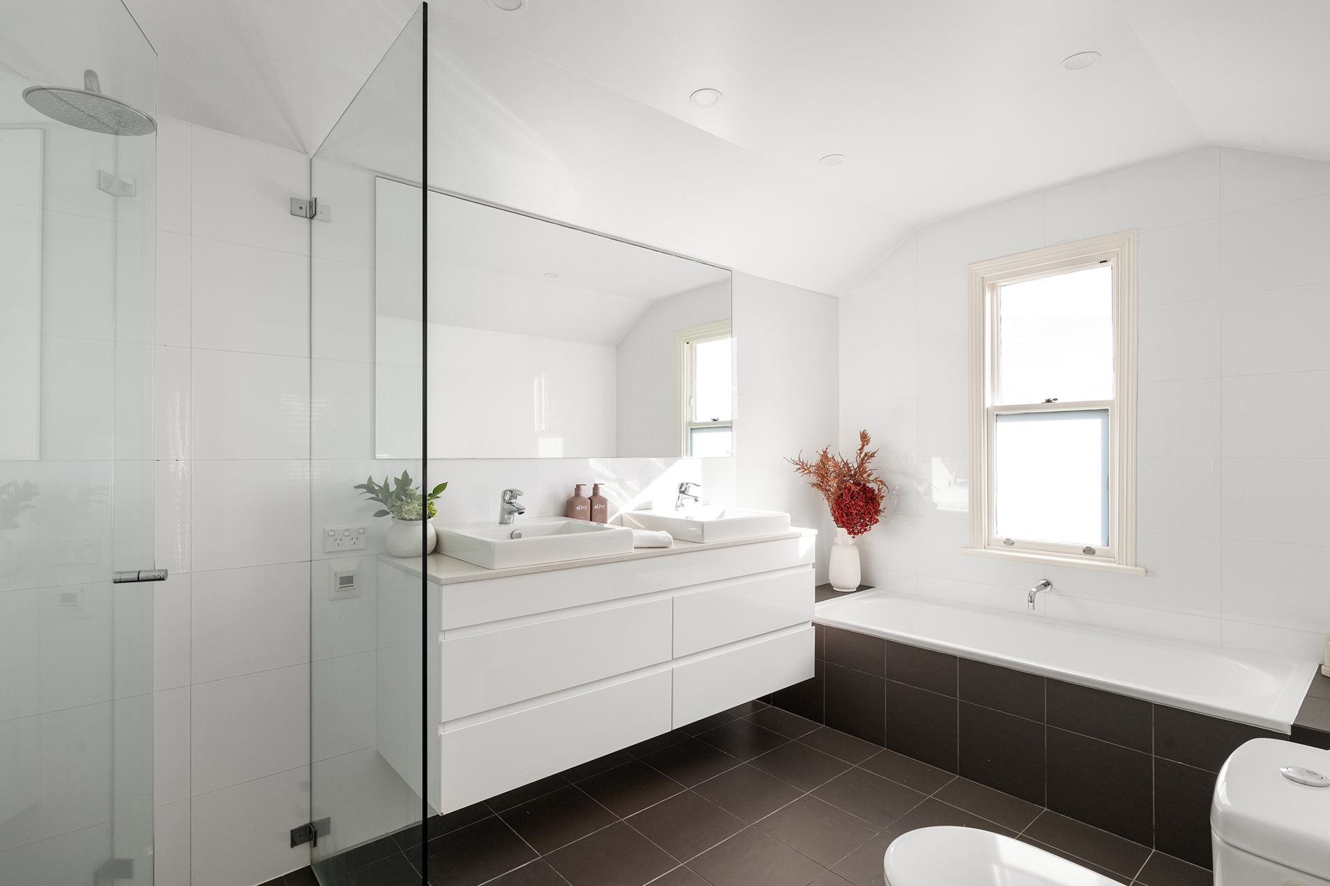 A bathroom with two sinks , a toilet , and a bathtub.