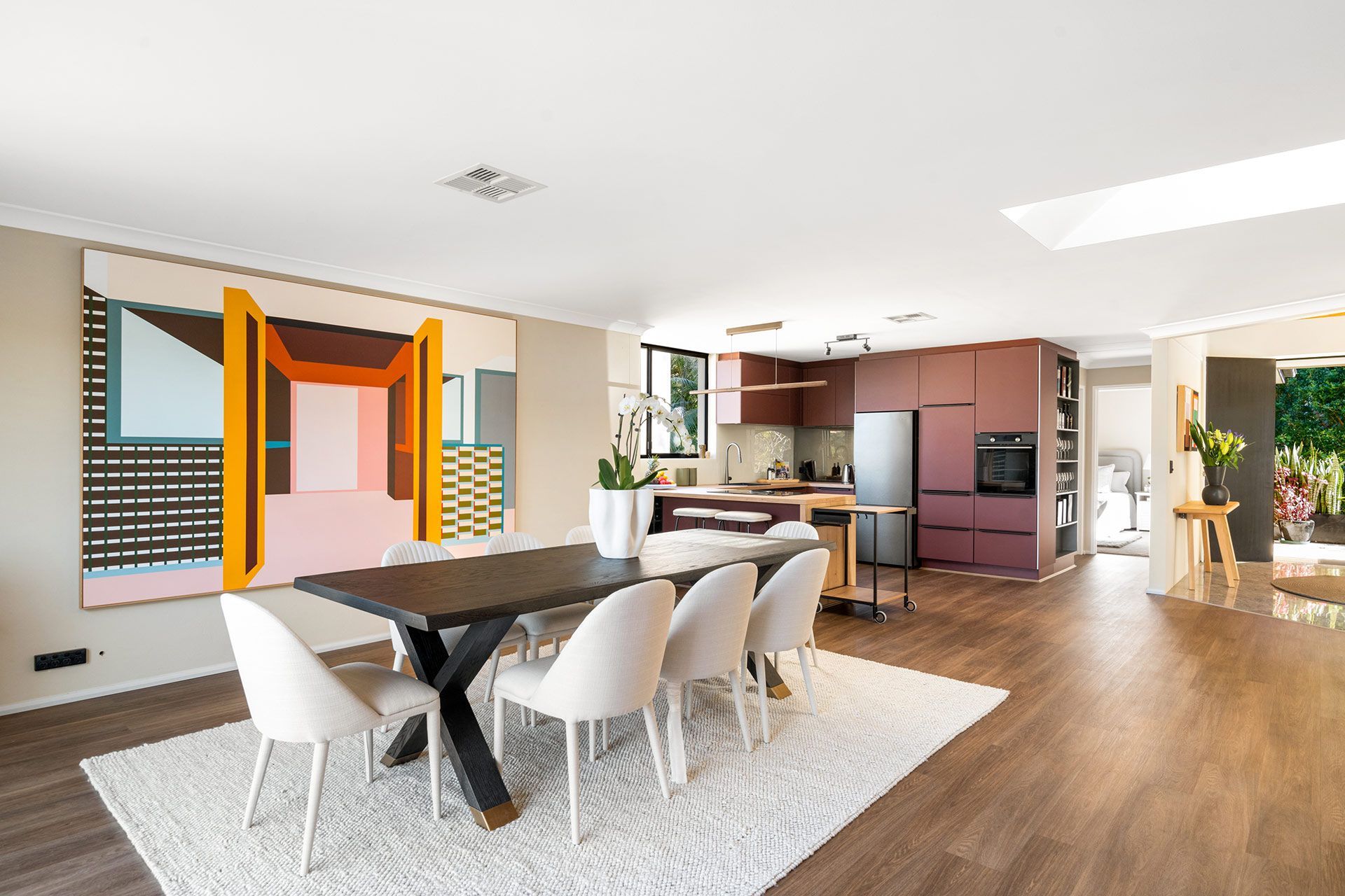 A dining room with a table and chairs and a large painting on the wall.