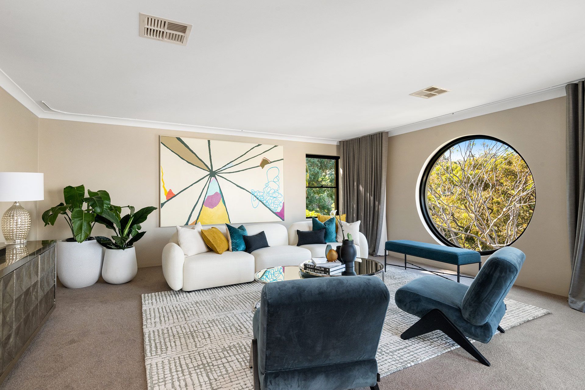 A living room with a couch , chairs , and a round window.