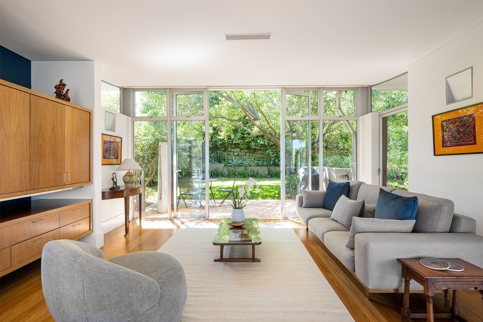 A living room with a couch , chair , coffee table and large windows.