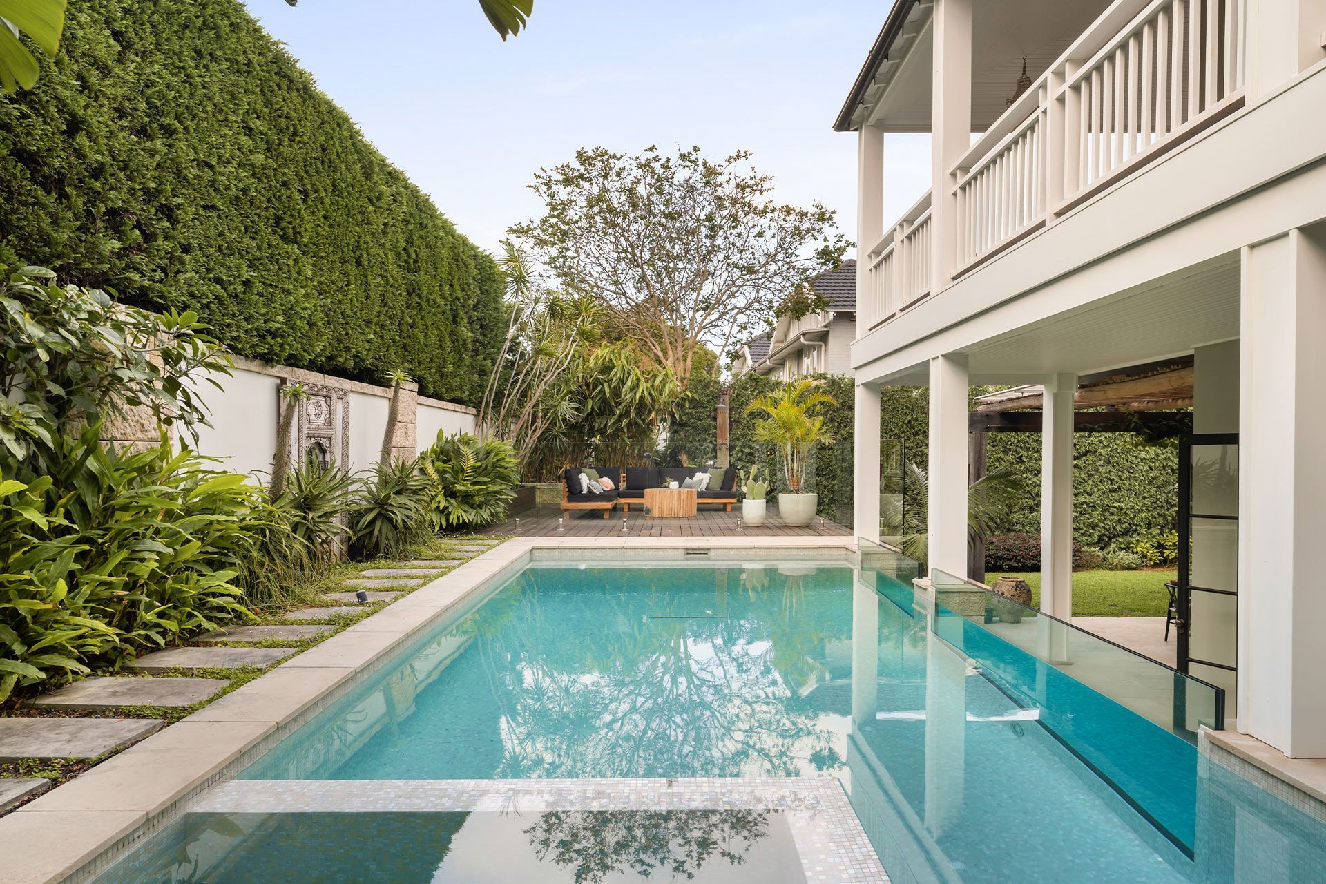 A large swimming pool is in the backyard of a house.