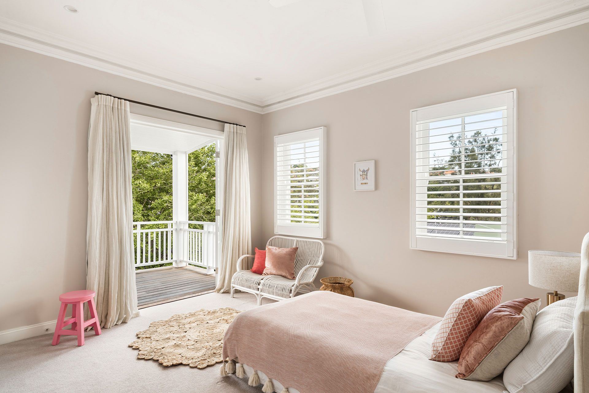 A bedroom with a bed , chair , rug and shutters.