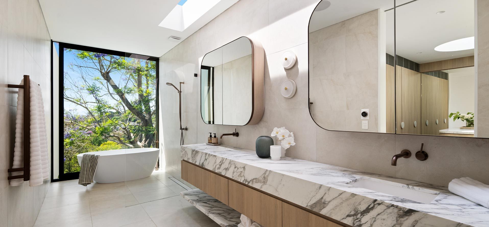 A bathroom with two sinks , two mirrors , a tub and a window.