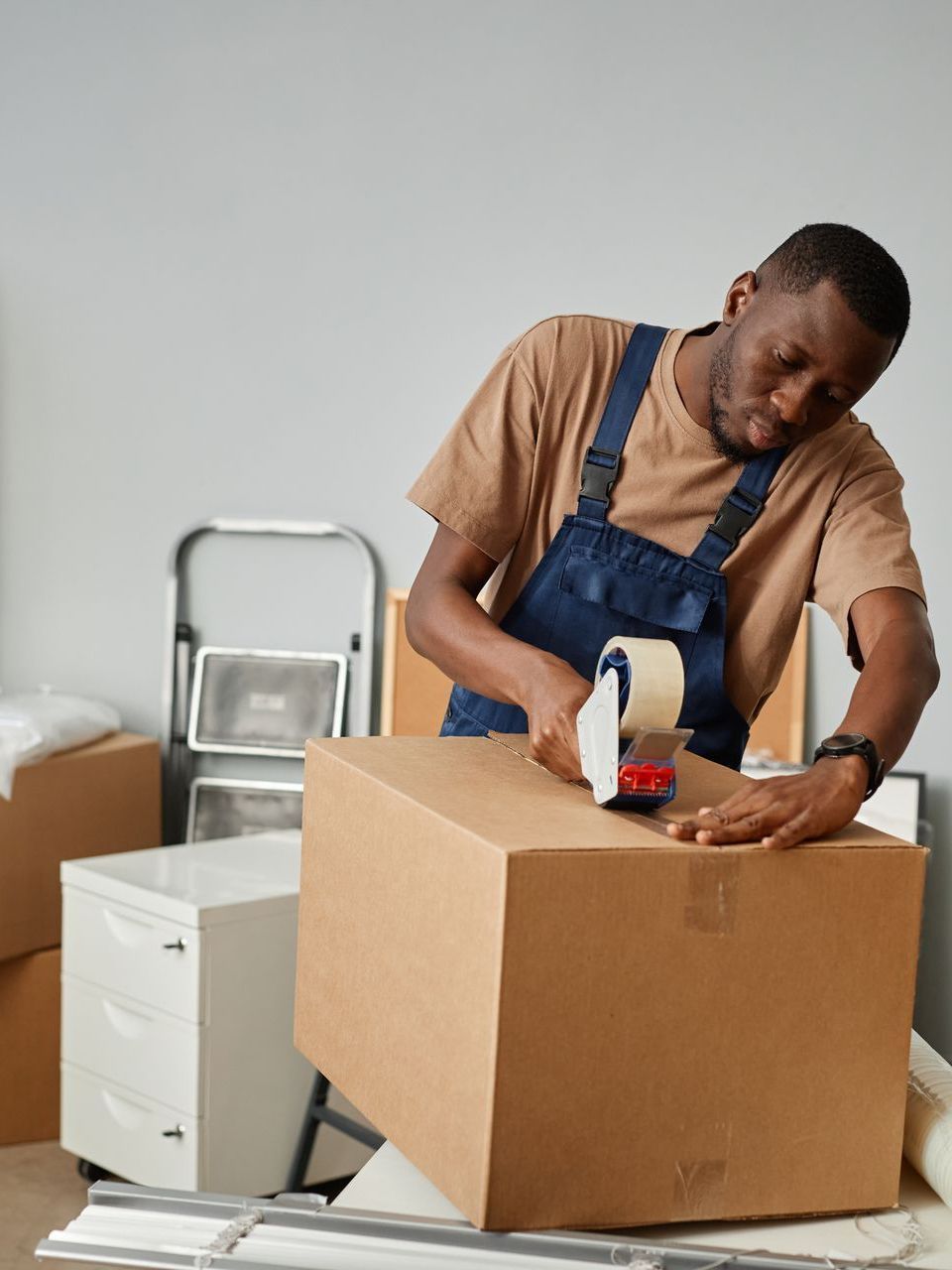 A man is wrapping a cardboard box with tape.