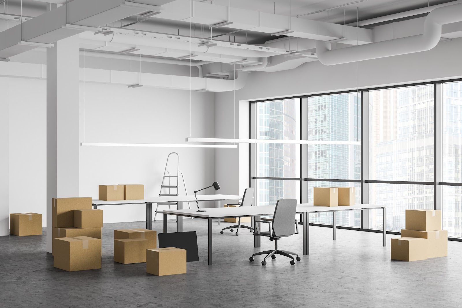 Empty office with moving boxes, desks, chair, and large windows.