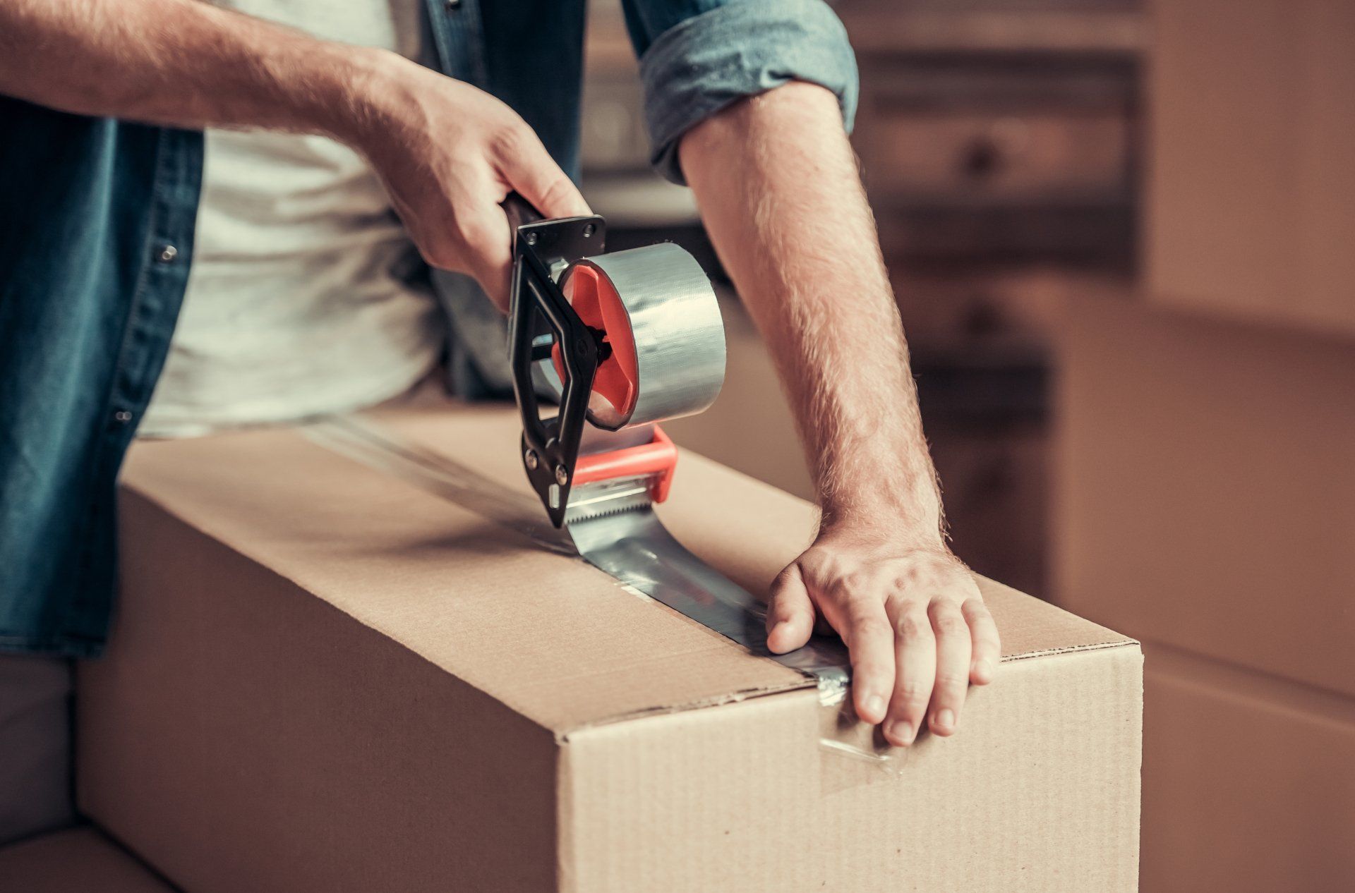 A man is taping a cardboard box with tape.