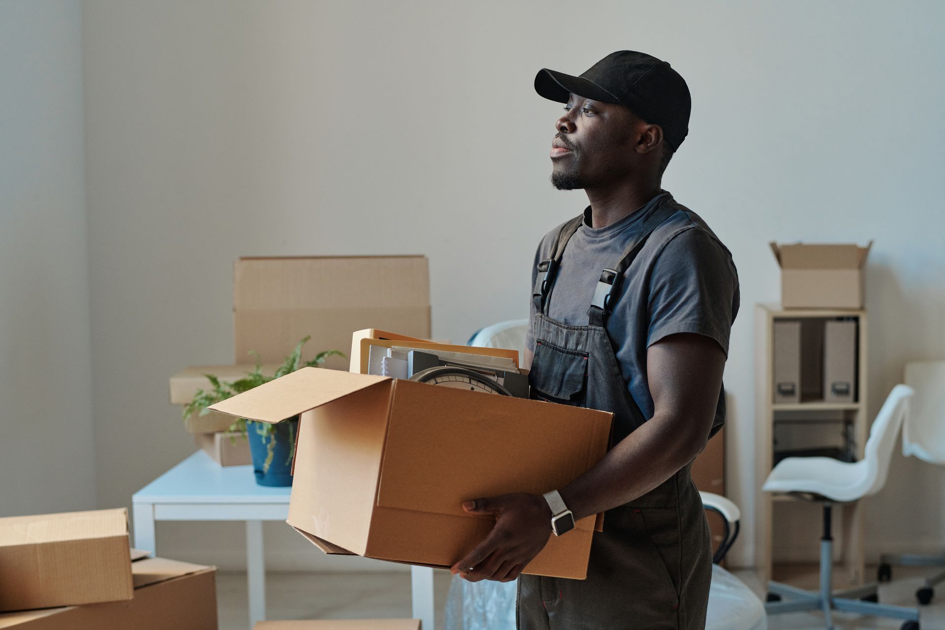 A man is carrying a cardboard box in a room.