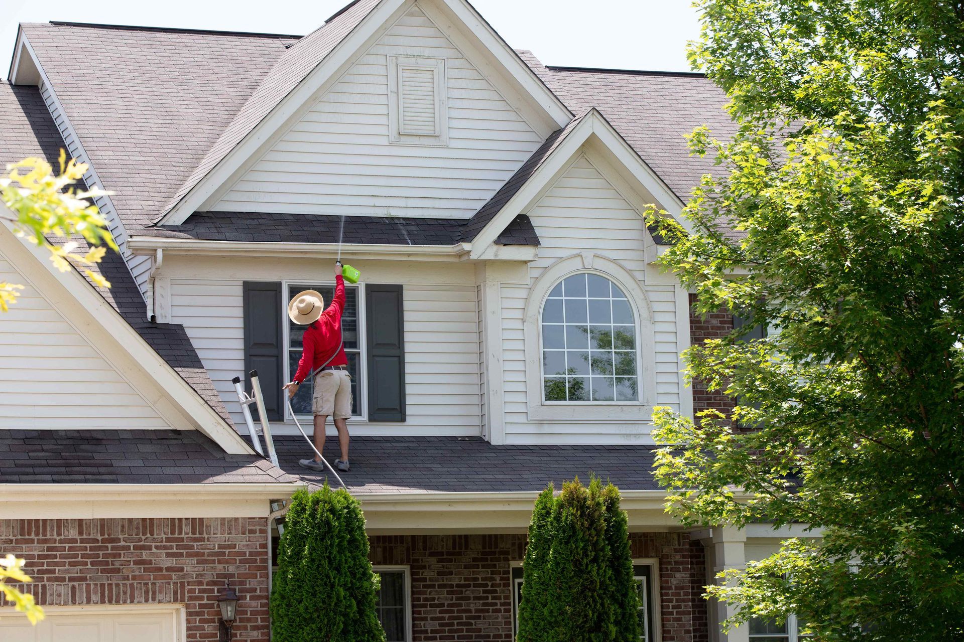 man pressure washing a house