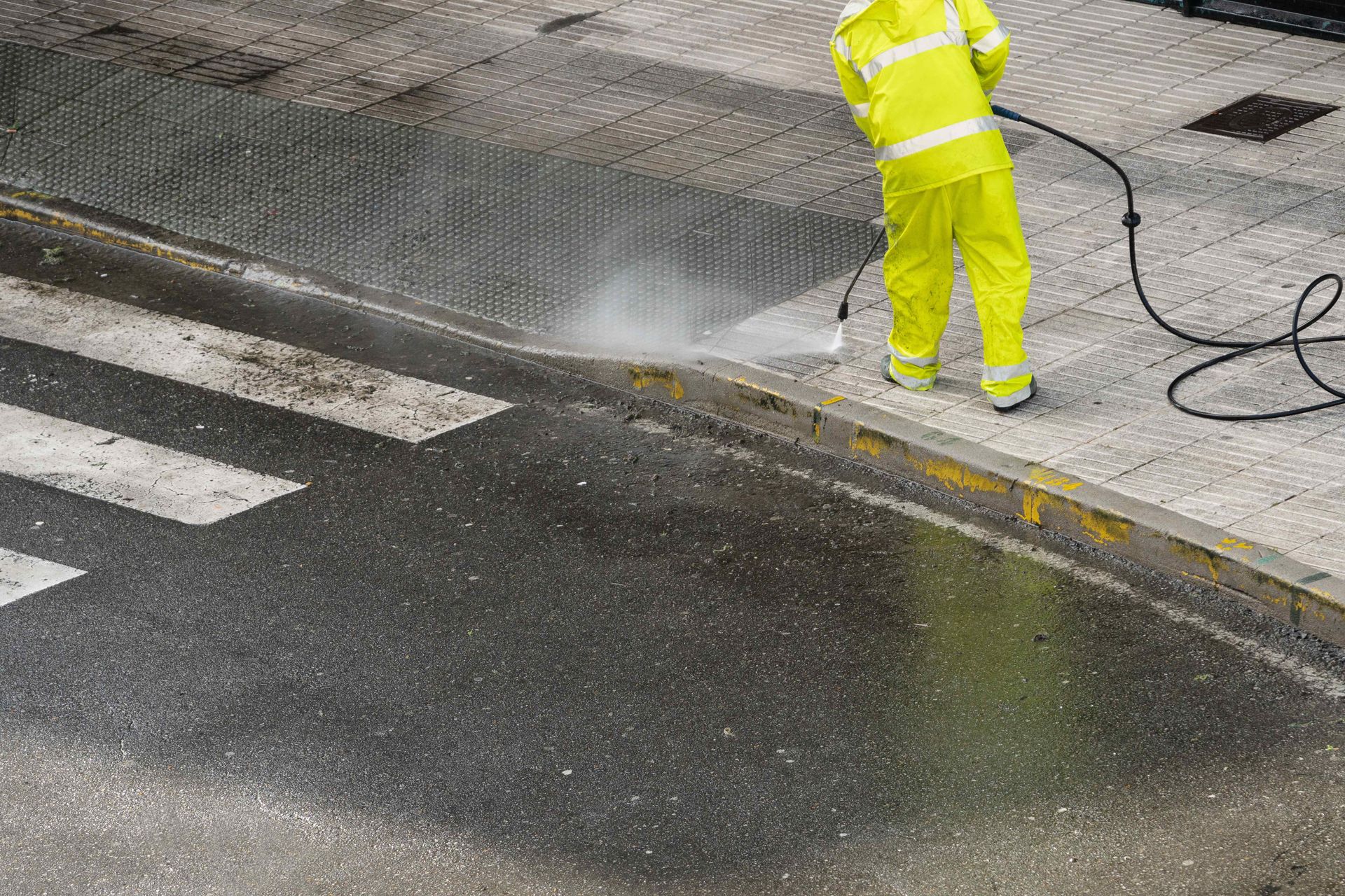 man pressure washing sidewalk
