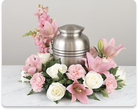 Silver urn surrounded by pink and white flowers on a white surface