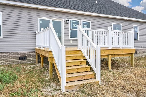 Wooden deck with white railing and steps leading to a house with gray siding.