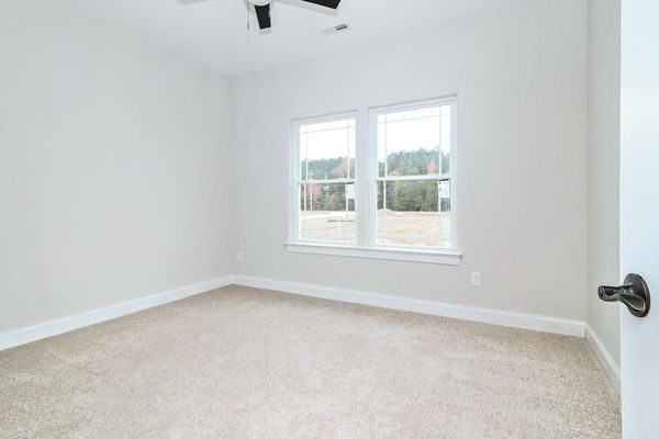 Empty room with beige carpet, light gray walls, two windows, and a ceiling fan.
