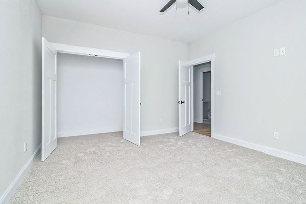 Empty room with closet and doorway, light gray walls, beige carpet.
