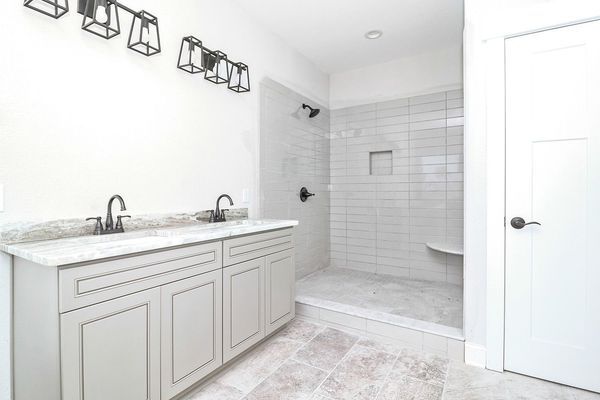 Bathroom with gray cabinets, white shower, and brushed nickel fixtures.