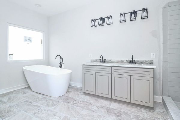 Modern white bathroom with a tub, vanity, and large window.