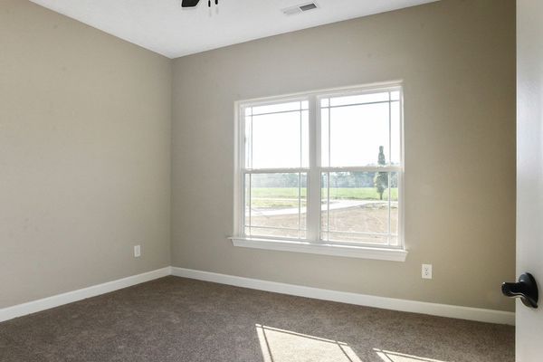 Empty room with neutral walls, window, and carpet.