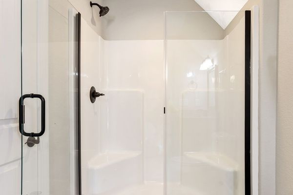 White and glass shower with black fixtures and door handle.