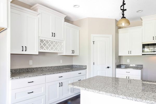 White kitchen with granite countertops, cabinets, and island. Black hardware and light fixture.