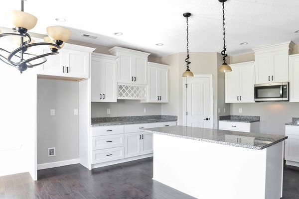 White kitchen with dark countertops, cabinets, and island. Dark floor, pendant lights, and appliances.