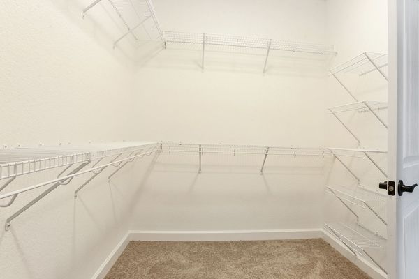 Empty white closet with wire shelving and beige carpet.