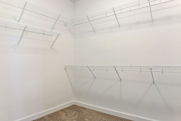 Empty white closet with wire shelving and carpeted floor.