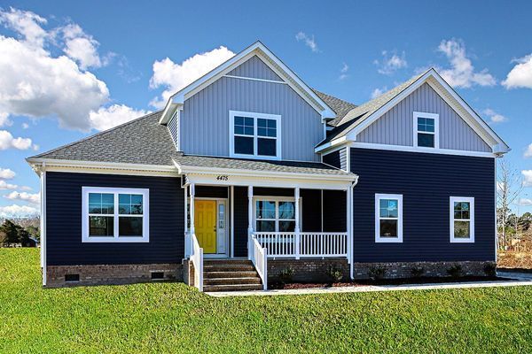 Two-story house with dark blue siding, white trim, and a yellow front door under a blue sky.