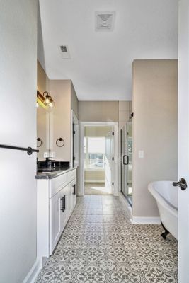 Bathroom with patterned floor, white vanity, and freestanding tub.