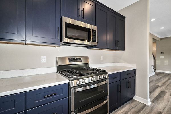 Kitchen with navy blue cabinets, stainless steel appliances, and white countertops.