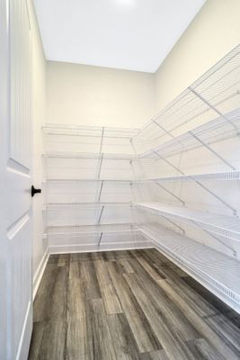 Empty pantry with white wire shelves, a grey wood-look floor, and a white door.
