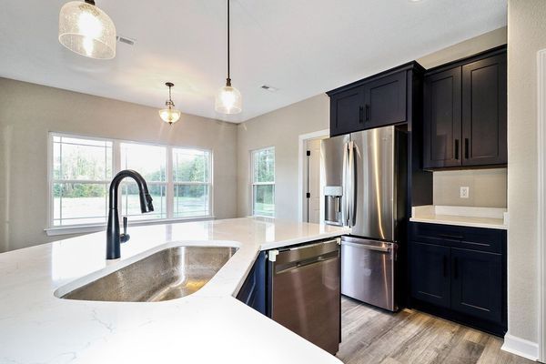 Modern kitchen with dark blue cabinets, stainless steel appliances, and white countertops.