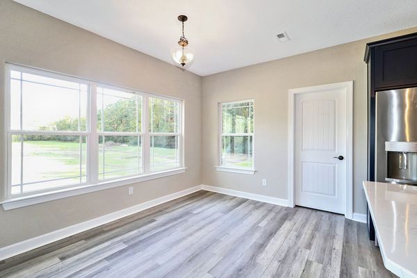Dining area with large windows, white door, gray flooring, and a hanging light fixture.