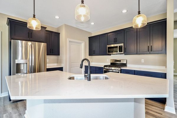 Modern kitchen with navy blue cabinets, stainless steel appliances, and white countertops.
