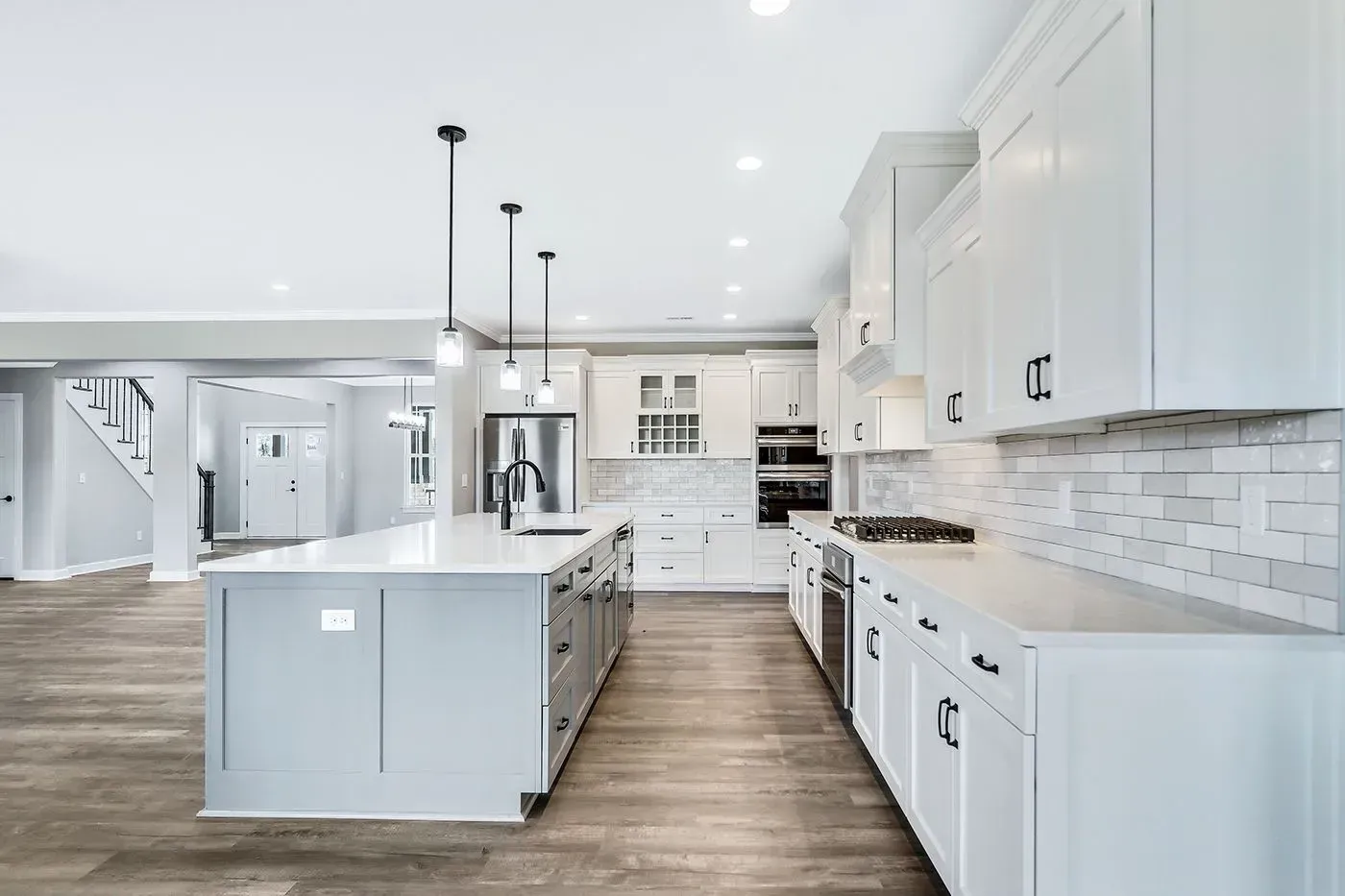 Modern, bright white kitchen with island, cabinets, and appliances.