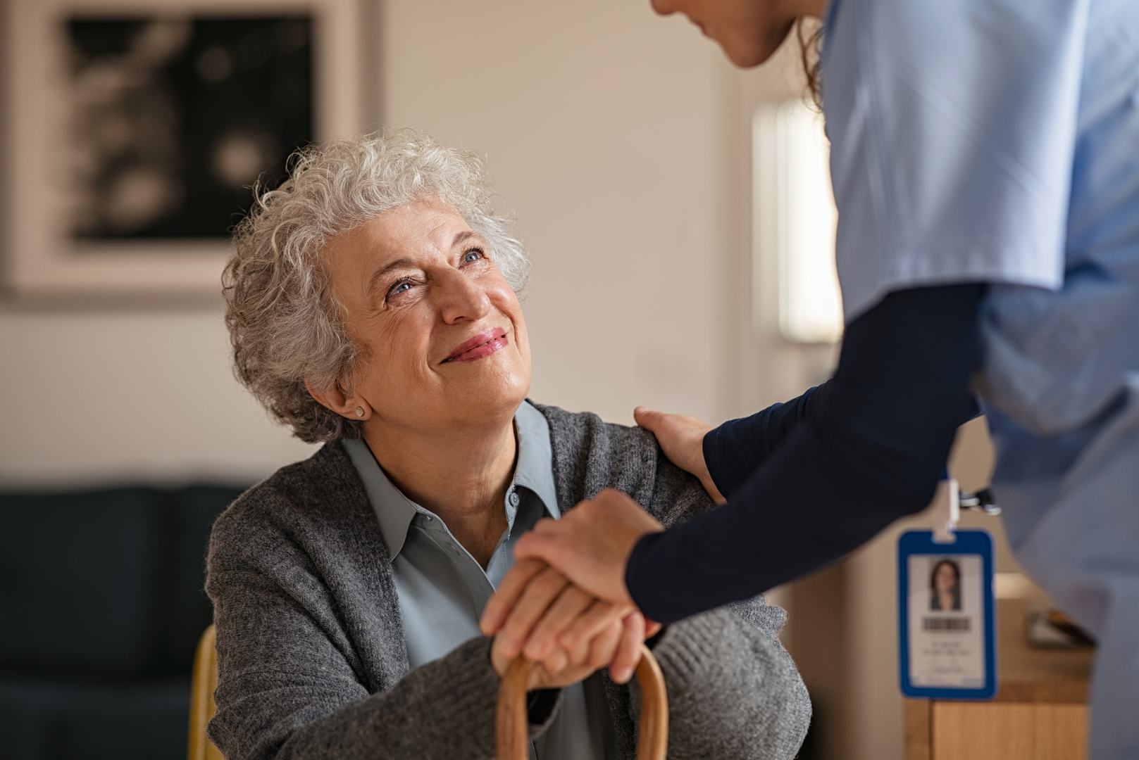 Caregiver holding hands with an older adult in a warm, supportive home setting.