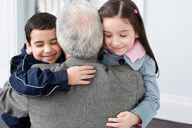 A man and two children are hugging each other.