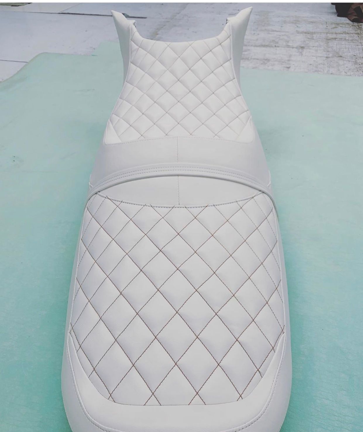Jet ski seat with orange diamond stitching on white vinyl