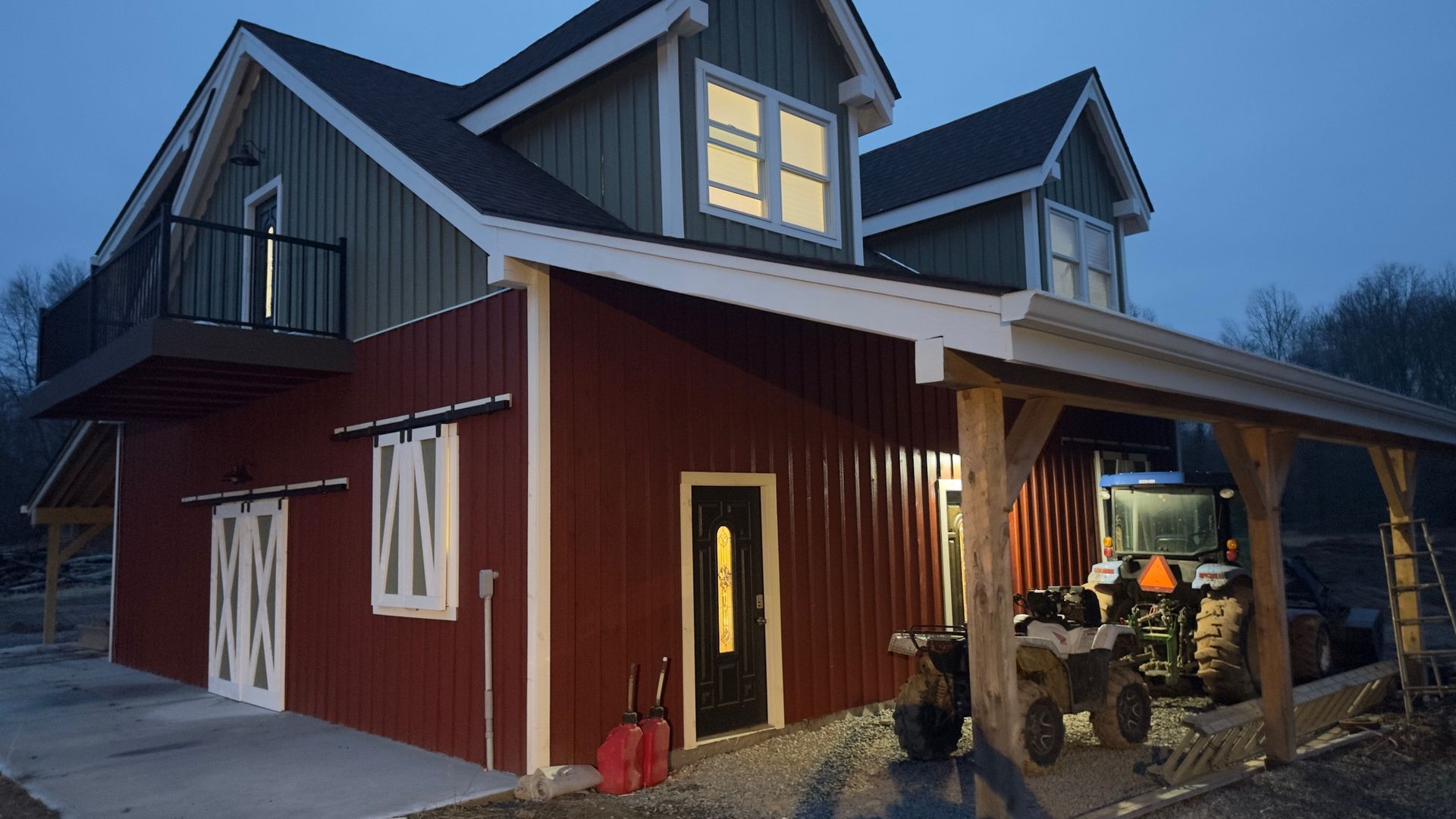 A two-story red barn with green dormers, a balcony by Central Timber Frame Supply. 