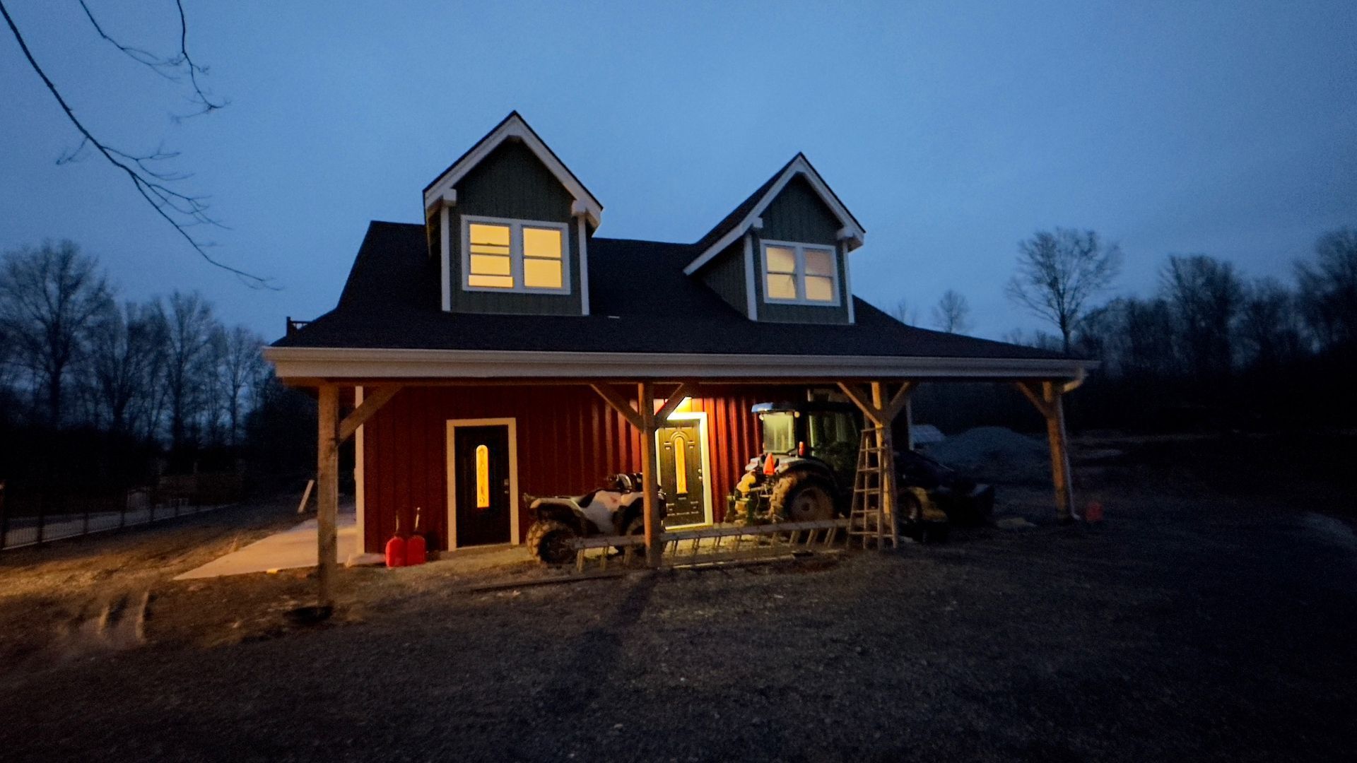 A red, two-story barn-style building with a porch, dormer windows, by Central Timber Frame Supply PA