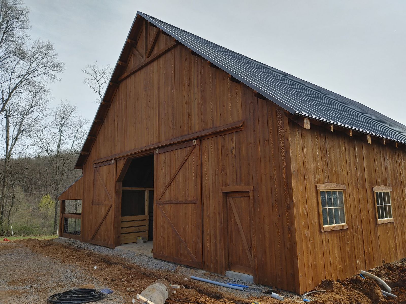 A rustic, brown wooden barn with a dark metal roof  by Central Timber Frame Supply. 