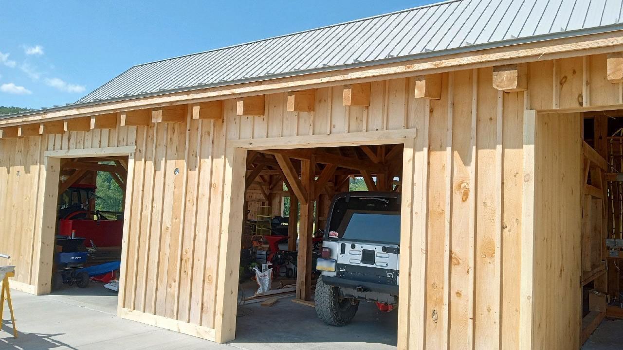 An unfinished wooden structure with two open garage bays by Central Timber Frame Supply. 