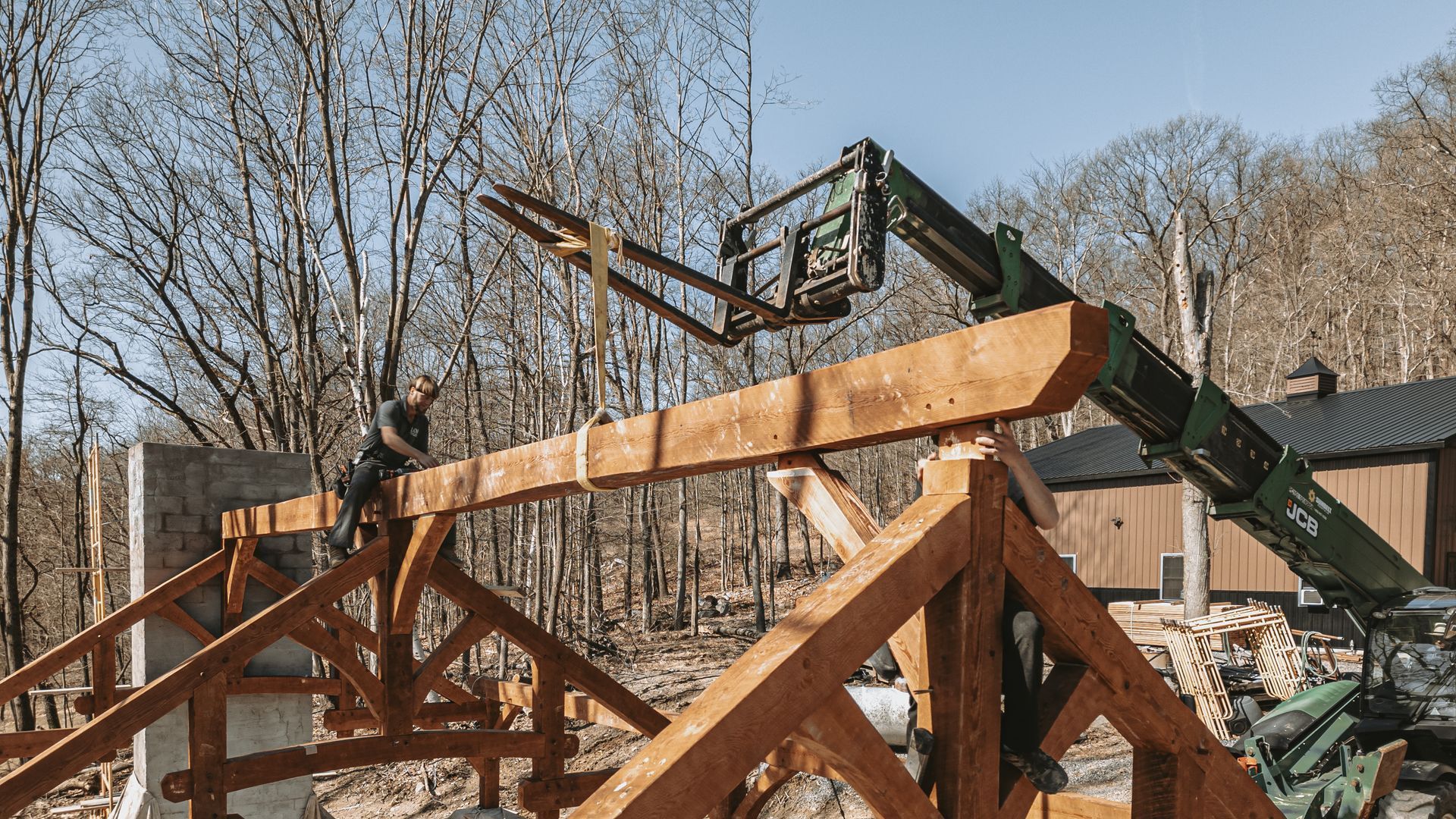 Positioning of a large wooden beam on the timber frame of a building by Central Timber Frame Supply. 