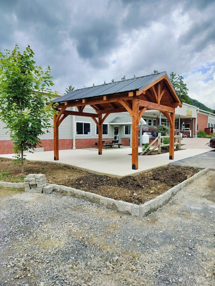 A wooden pavilion with a dark metal roof. built by Central Timber Frame Supply available for wholesale across the US.