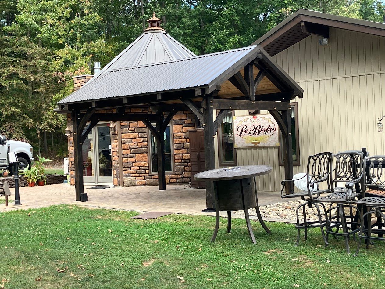 A wooden pavilion by Central Timber Frame Supply available for wholesale across the United States with a dark metal roof.