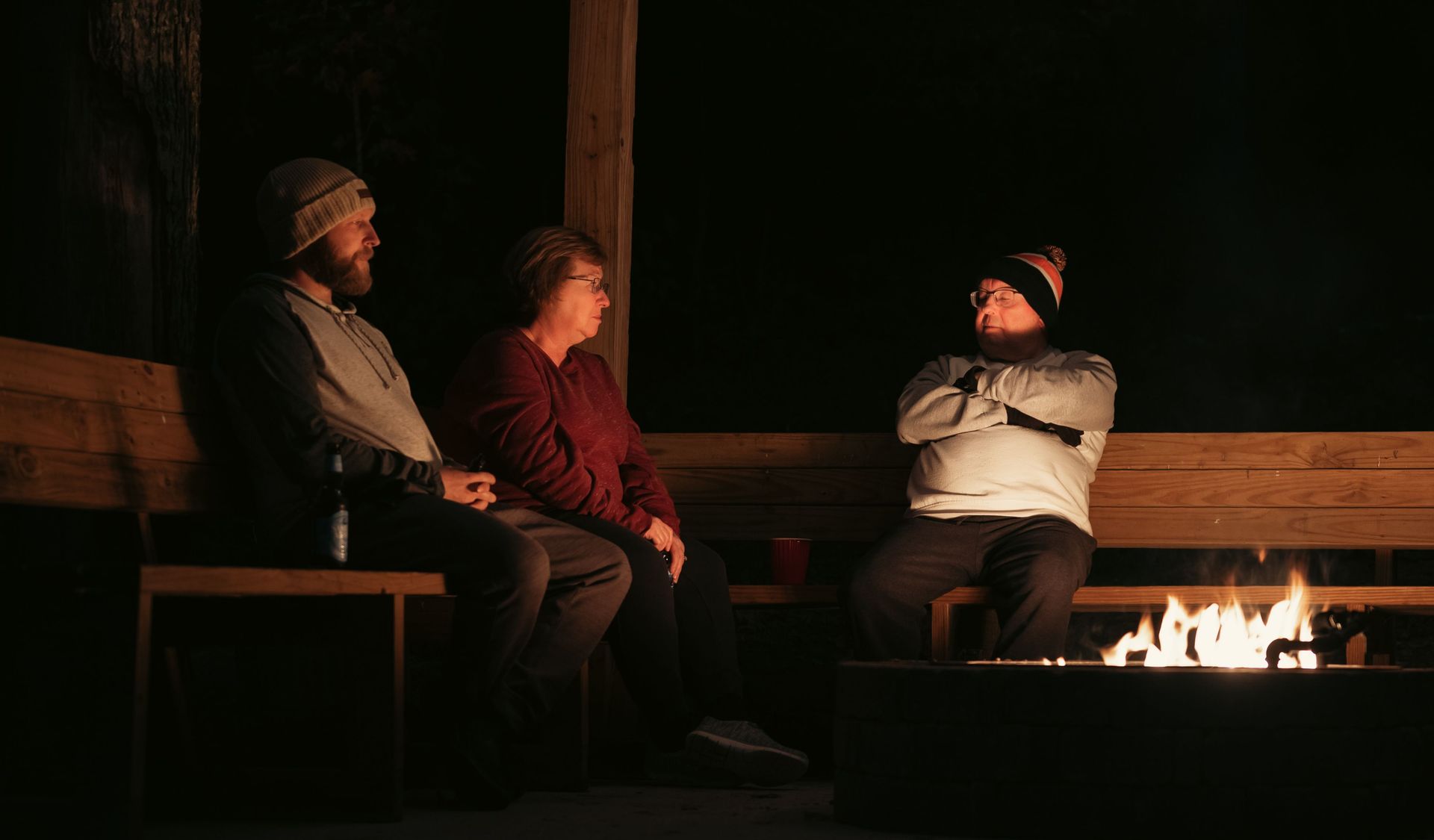 Three people gathering around an outdoor fire pit at night during fall in Wisconsin.
