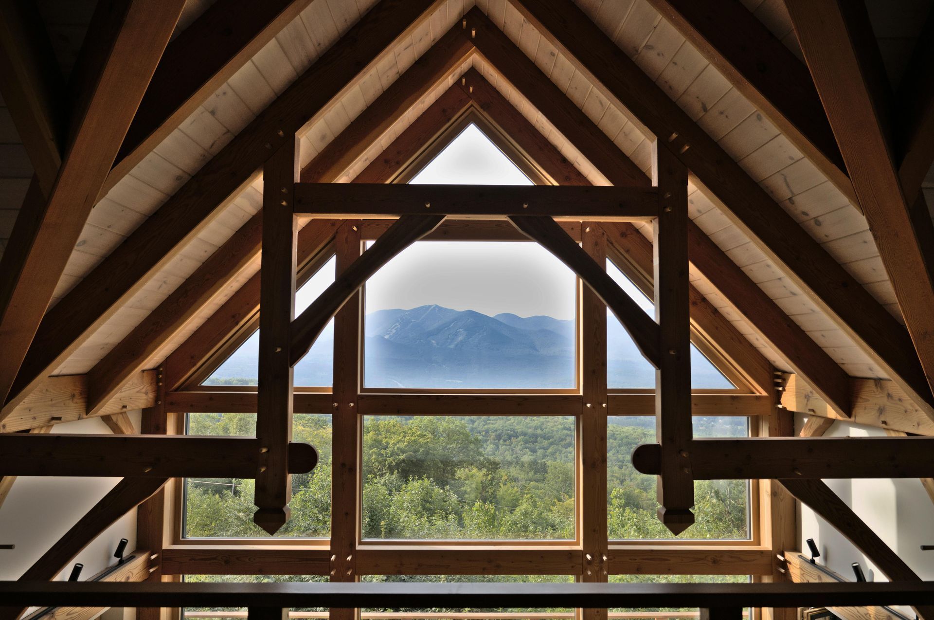 Wooden A-frame cabin interior framing a mountain view through a central window
