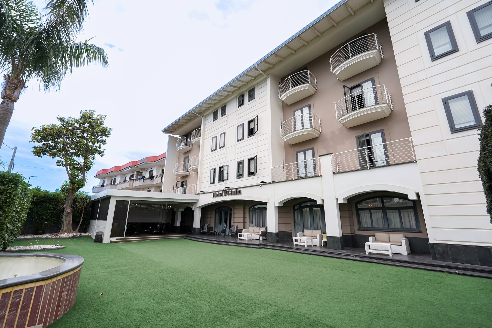 Cortile di un condominio beige con balconi ad arco e prato verde.