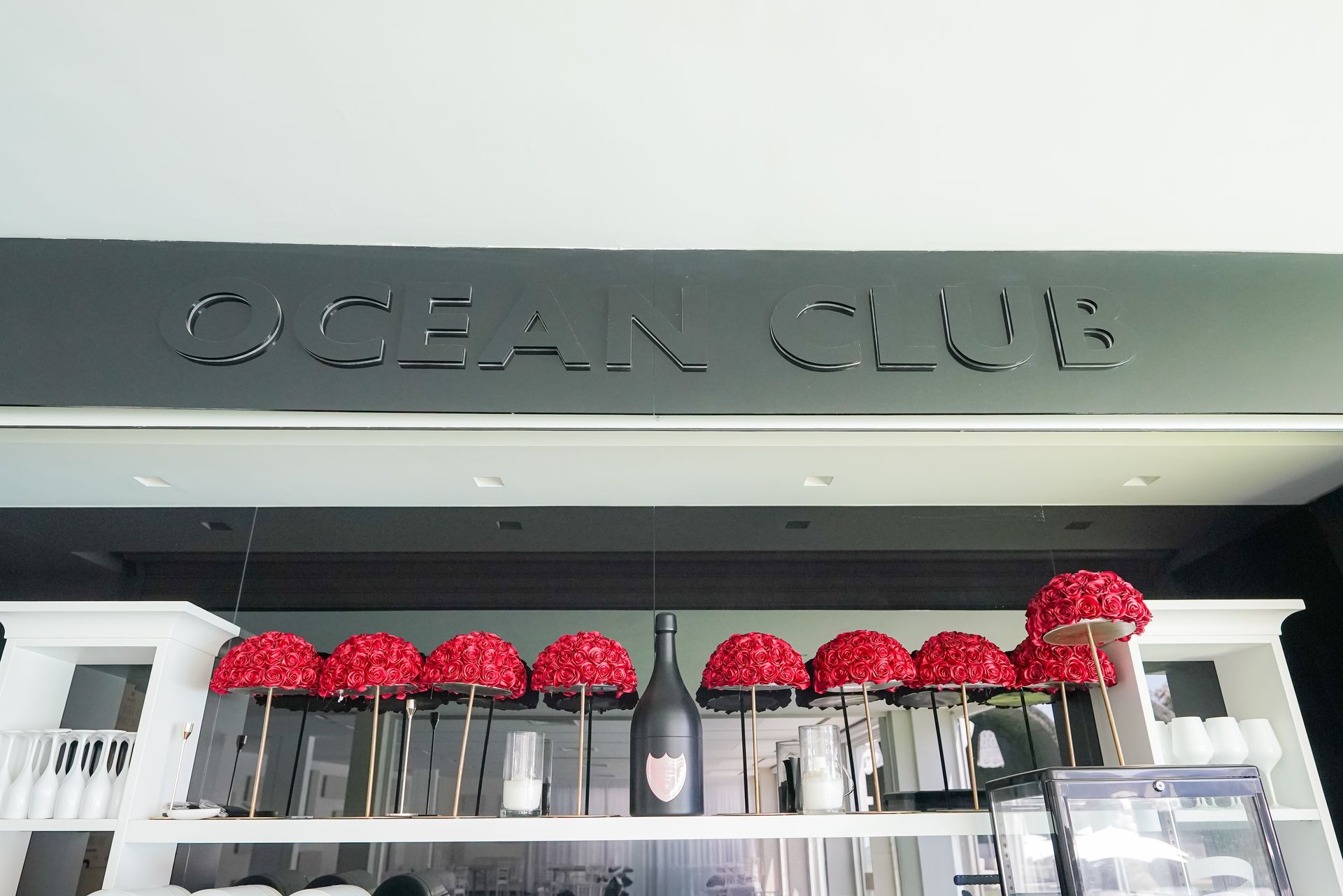 La vetrina dell'Ocean Club con ombrelloni rossi e tavolini all'esterno.