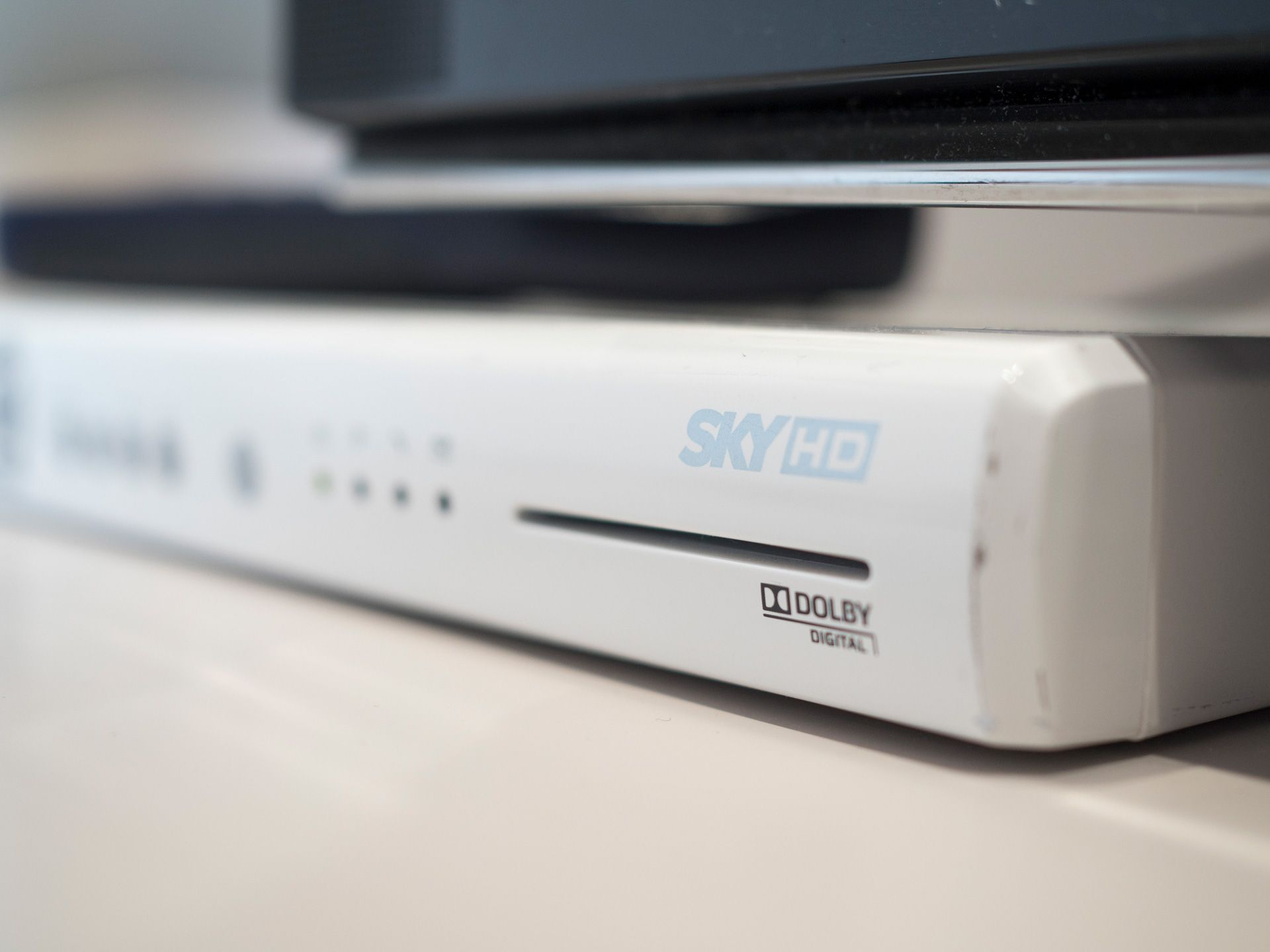 Primo piano di un decoder SKY HD bianco su uno scaffale, con spie di stato e logo Dolby Digital.