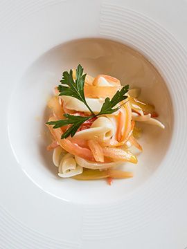 Piatto bianco con una piccola porzione di insalata di pasta guarnita con prezzemolo e salsa cremosa.