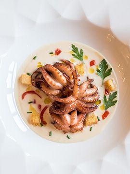 Carpaccio di polpo con erbe aromatiche e verdure su un piatto bianco